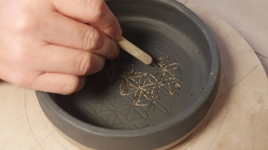 Hand carving pattern inside clay bowl.