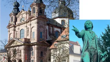Barockkirche neben Bronze-Statue im Freien.