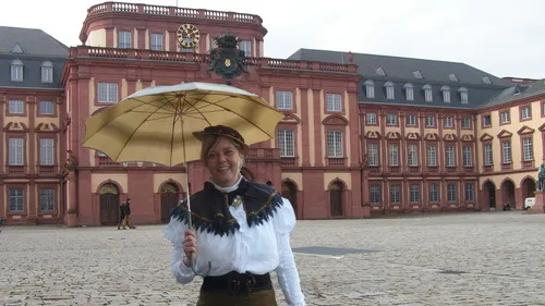 Person holding umbrella in front of historical building.