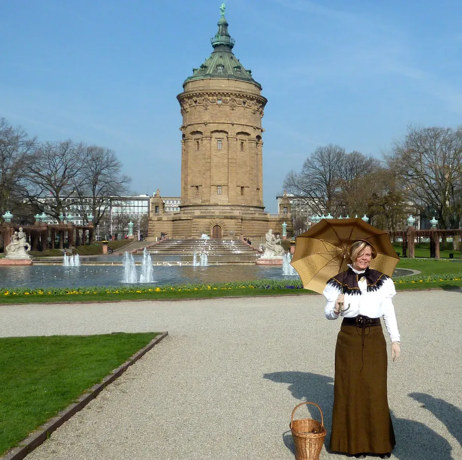 Frau mit Schirm vor Wasserturm.