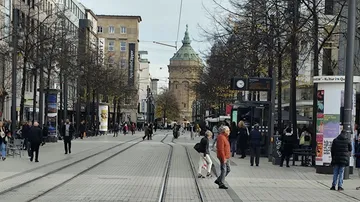 People walking on city street with tram lines.