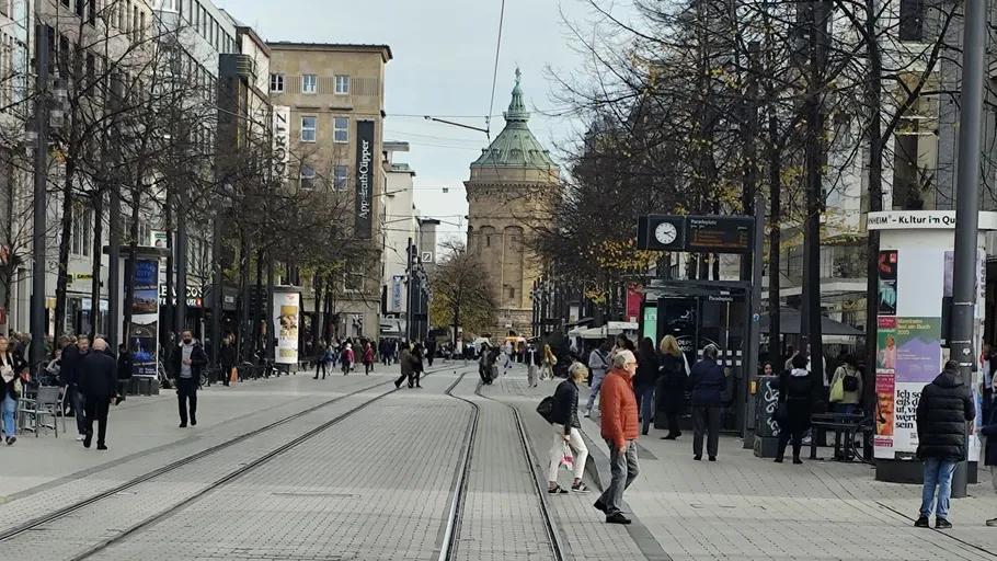 Menschen gehen auf Stadtstraße mit Straßenbahnschienen.