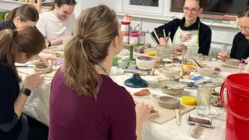 Gruppe töpfert gemeinsam an einem Tisch drinnen.