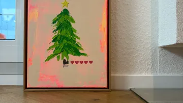 Framed Christmas tree painting with pink background.