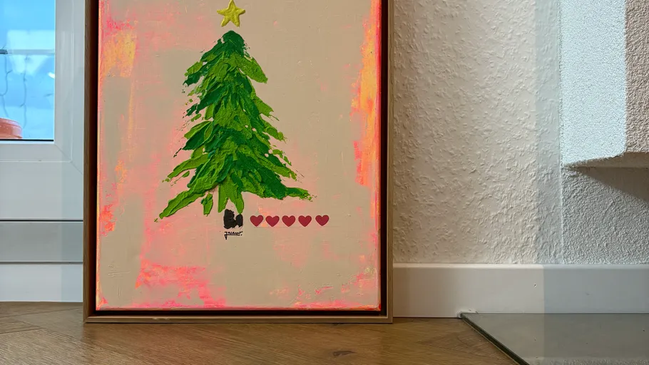 Gerahmtes Weihnachtsbaumgemälde mit rosa Hintergrund.