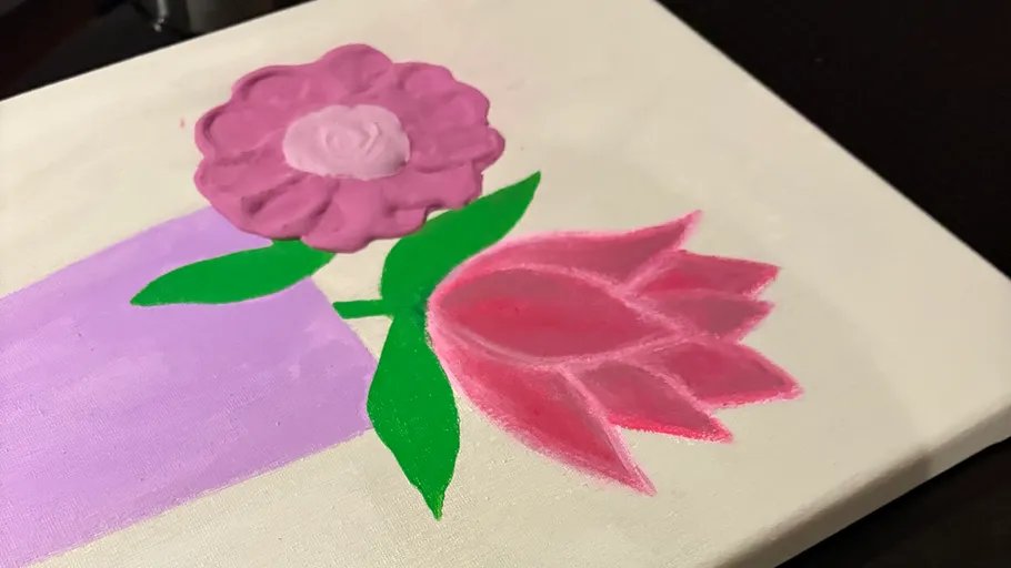 Painted flowers on canvas with green leaves.