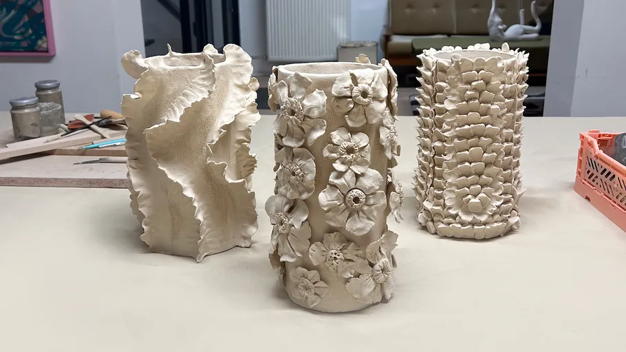 Drei verzierte Keramikvasen auf Tisch.