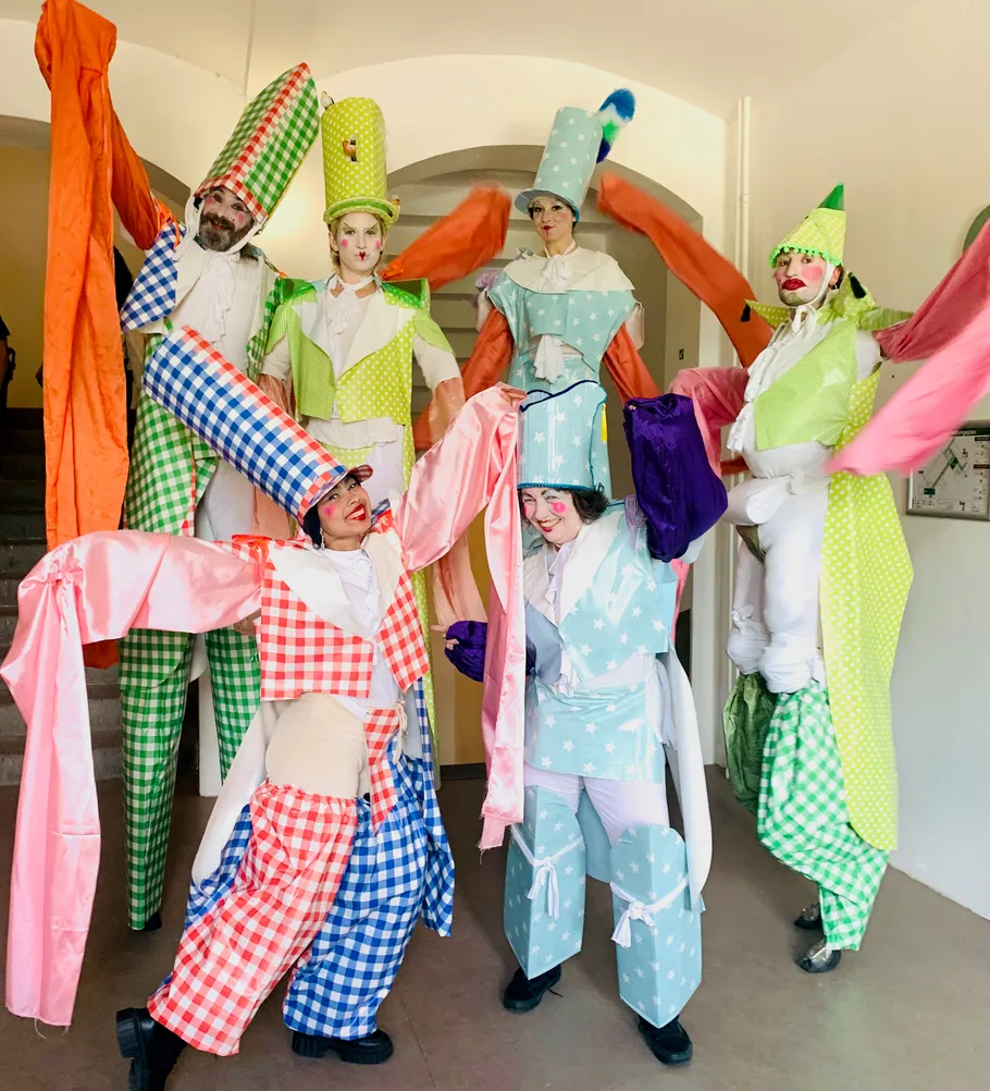 Performers in colorful costumes pose indoors.