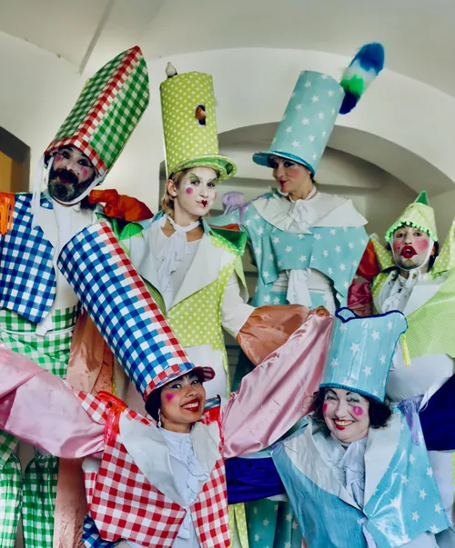 People in colorful clown costumes smiling indoors.