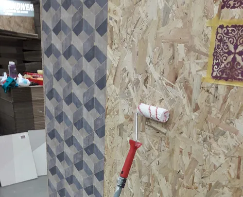 Farbroller an strukturierter Wand in Werkstatt.