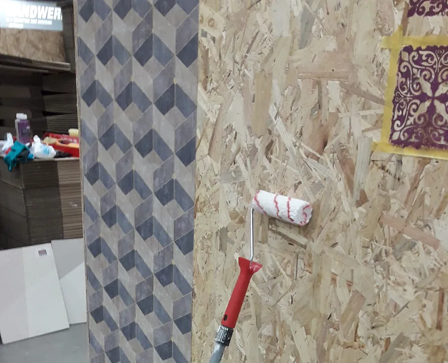 Paint roller on textured wall in workshop.