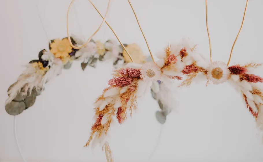 Dried floral crowns hanging against white background.