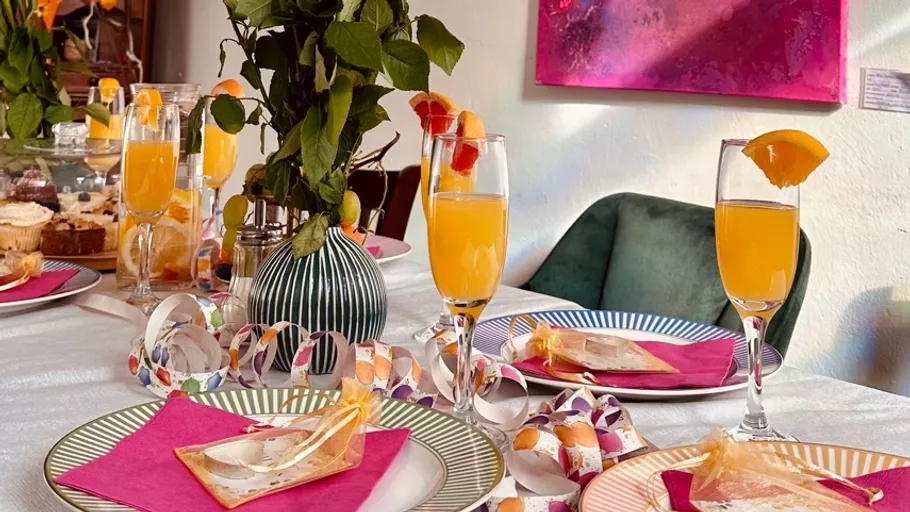 Dekorierter Tisch mit Cocktails und Tellern.