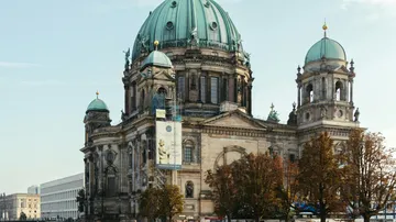 Große historische Kathedrale mit grünen Kuppeln, Bäume ringsum.