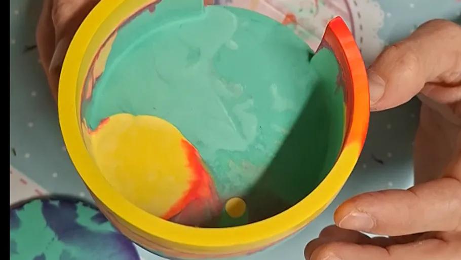 Hands holding colorful, abstract-designed bowl.