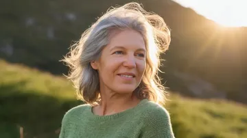 Frau lächelt draußen im Sonnenlicht.