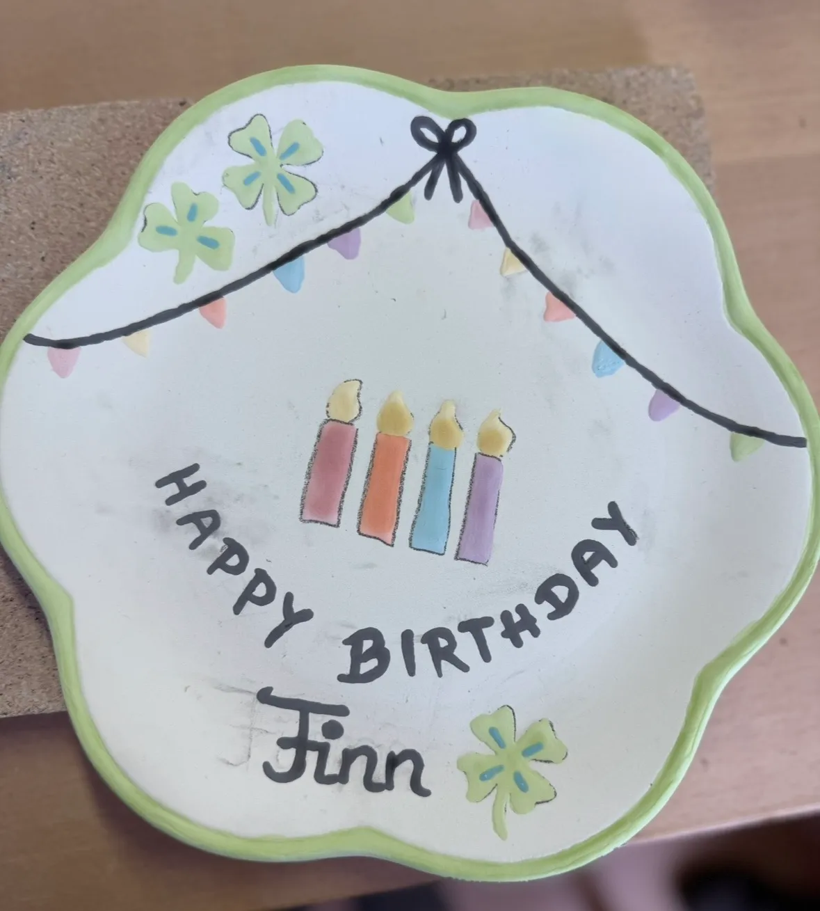 Dekorativer Geburtstags-Teller mit Kerzen und Kleeblättern.