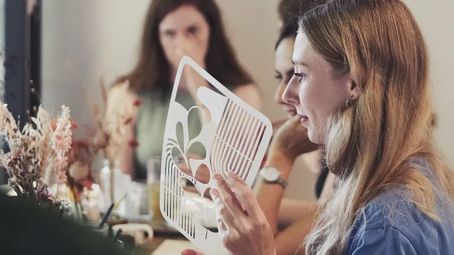 Woman holding stencil in a workshop setting.