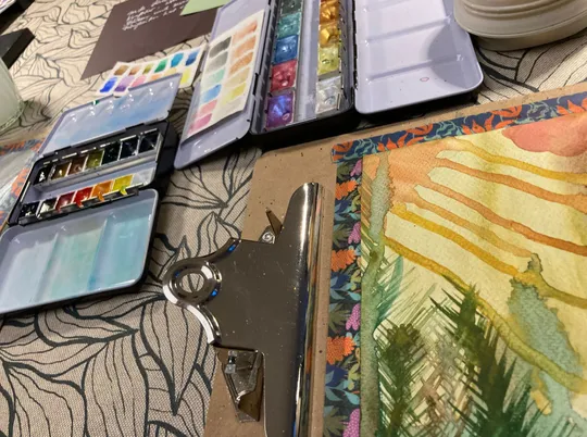 Watercolor paints and painting on table.