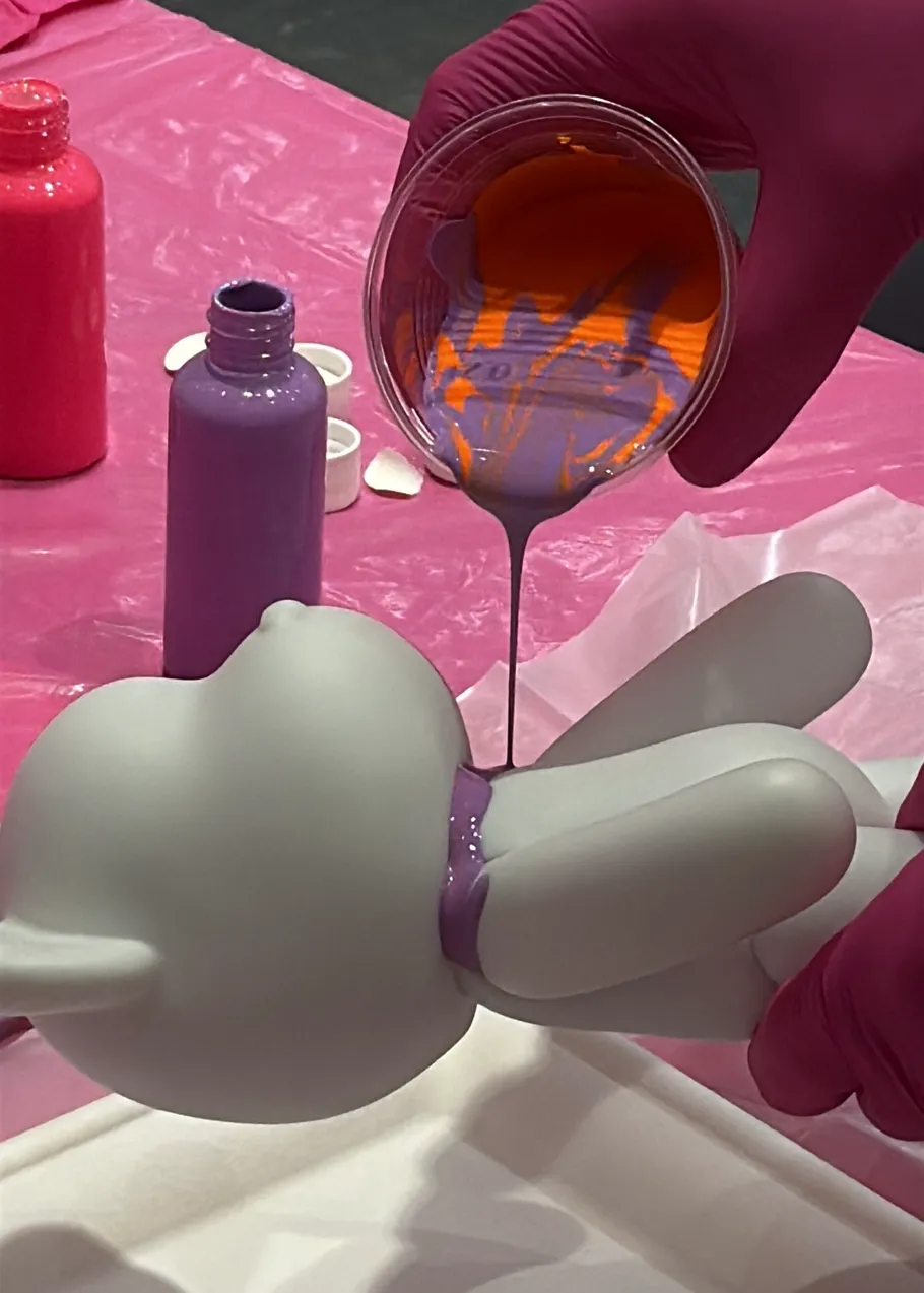 Toy figurine being painted with colorful paint.