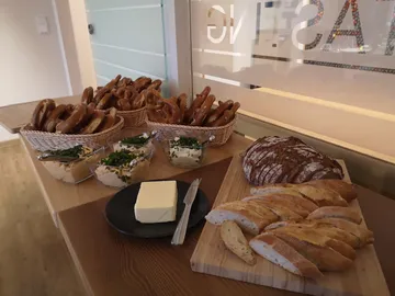 Pretzels and breads are on a table with butter.