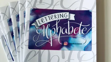 Lettering booklets stacked, colorful cover design.