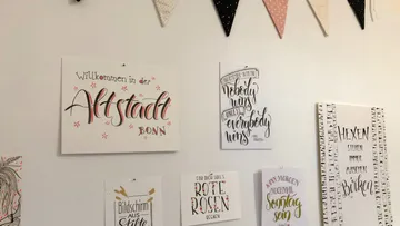 Wand mit dekorativen Spruchpostern und Wimpeln.