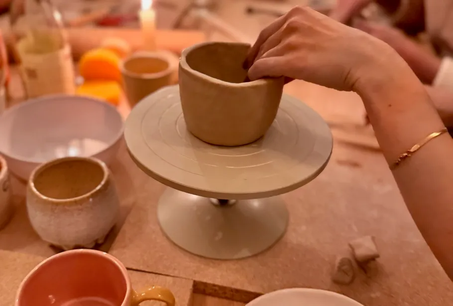 Hand shaping pottery on a turntable, indoors.