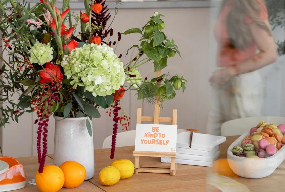 Blumen und Früchte auf Tisch mit Motivationsschild.
