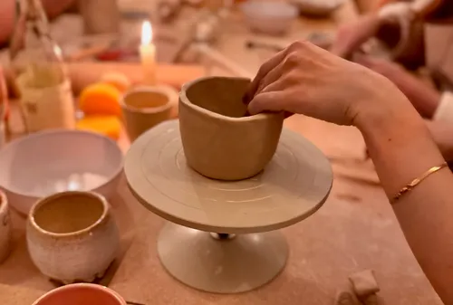 Hand formt Tontopf auf Drehscheibe.