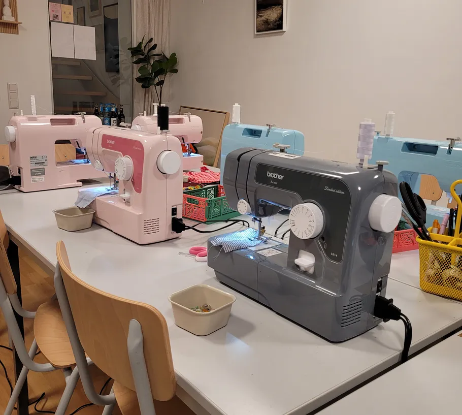 Nähmaschinen auf Tisch in Werkstatt.