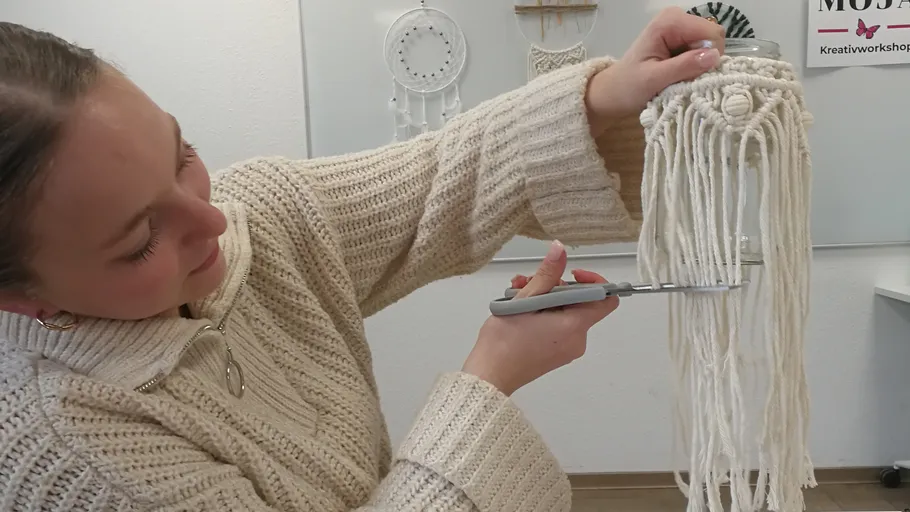 Person cutting macramé strings in a creative workshop.
