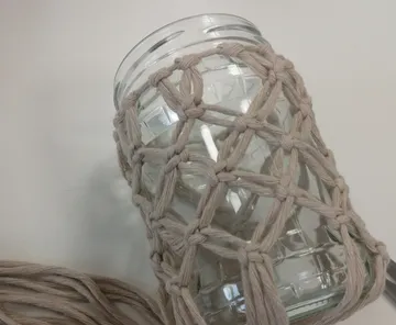 Glass jar wrapped in macramé string.