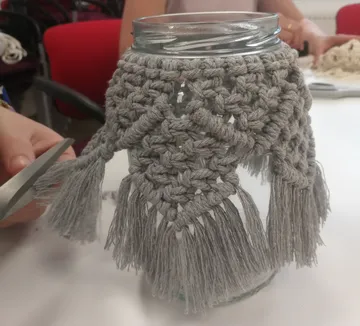 Jar with macramé cover being crafted.