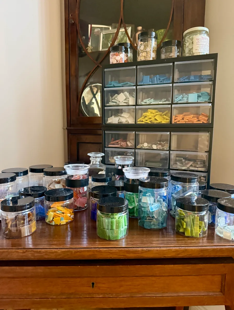 Jars of colored tiles on wooden table.