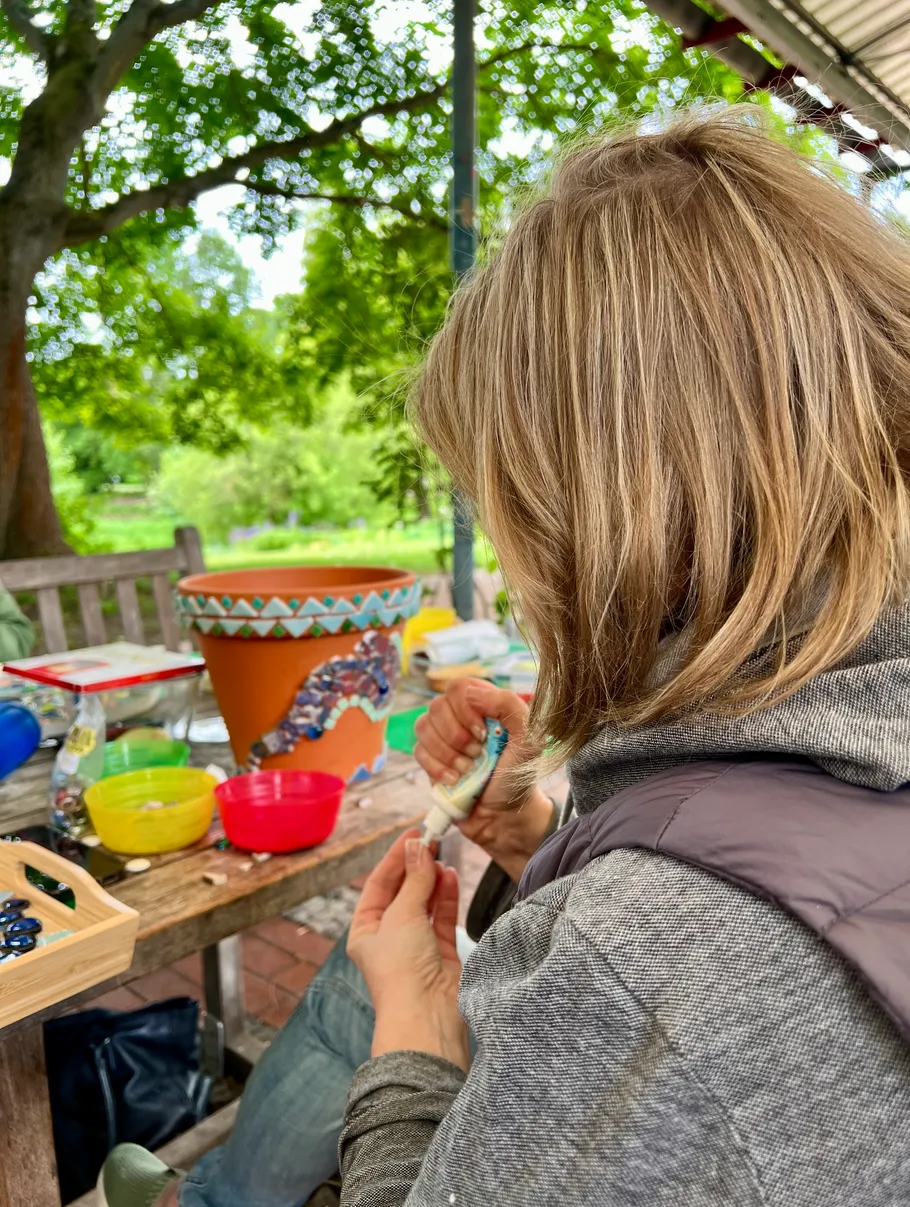 Person decorating pot with paint outdoors.
