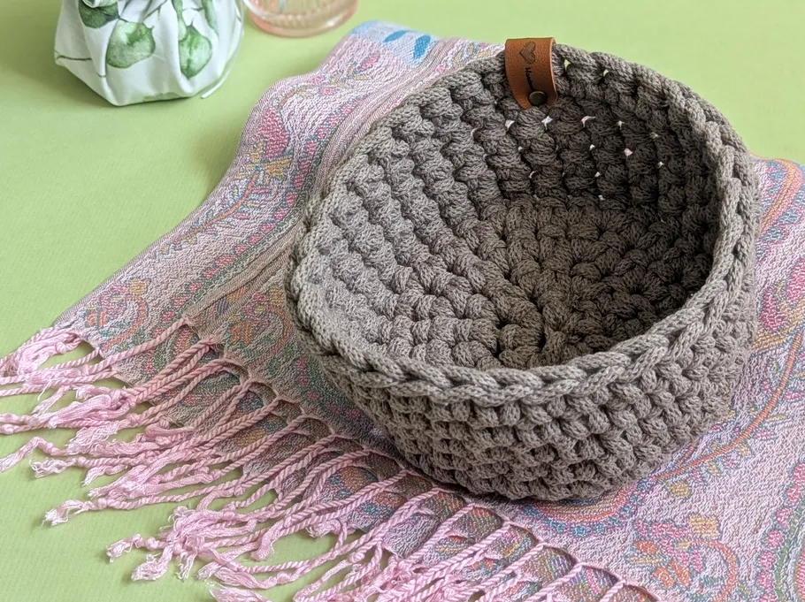 Crocheted basket on fringed textile cloth.