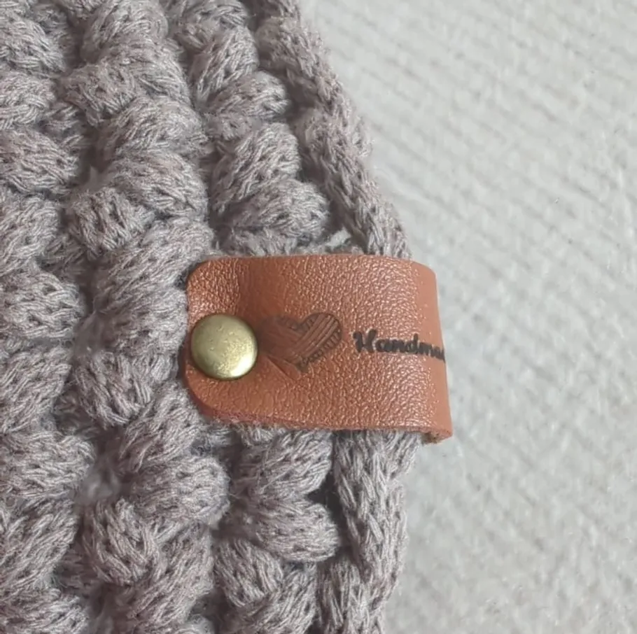 Gehäkelte Decke mit Lederetikett 'Handmade'.