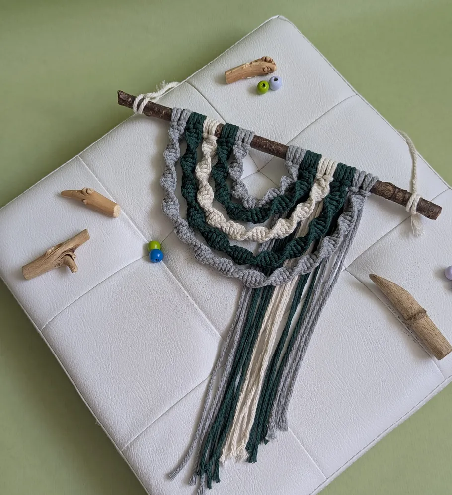 Macrame wall hanging on white cushion with beads.