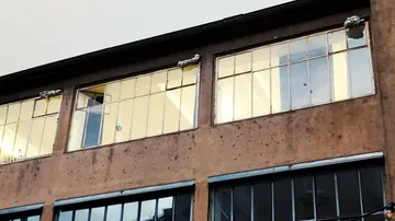 Fassadenansicht mit großen Fenstern, Seile sichtbar.