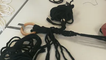 Black yarn tied to wooden ring on table.