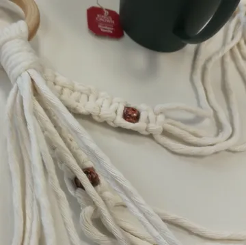 Macrame with beads beside a cup.