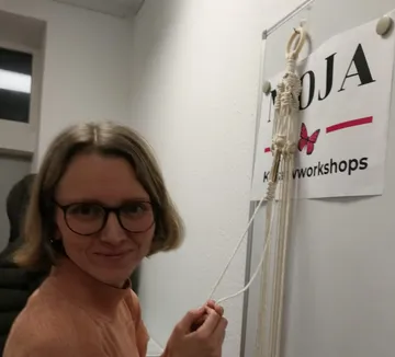 Woman tying macramé in craft workshop.