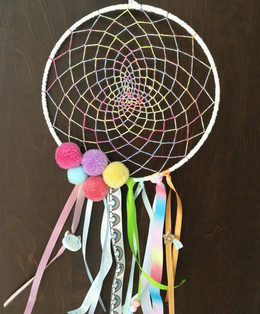 Colorful dreamcatcher with pom-poms and ribbons.