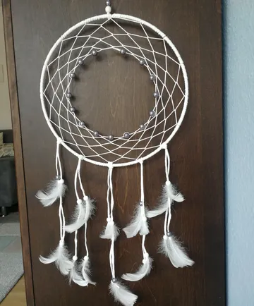 White dreamcatcher hangs on wooden door.