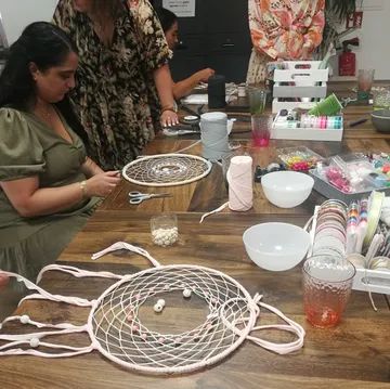 People crafting dreamcatchers at a wooden table.