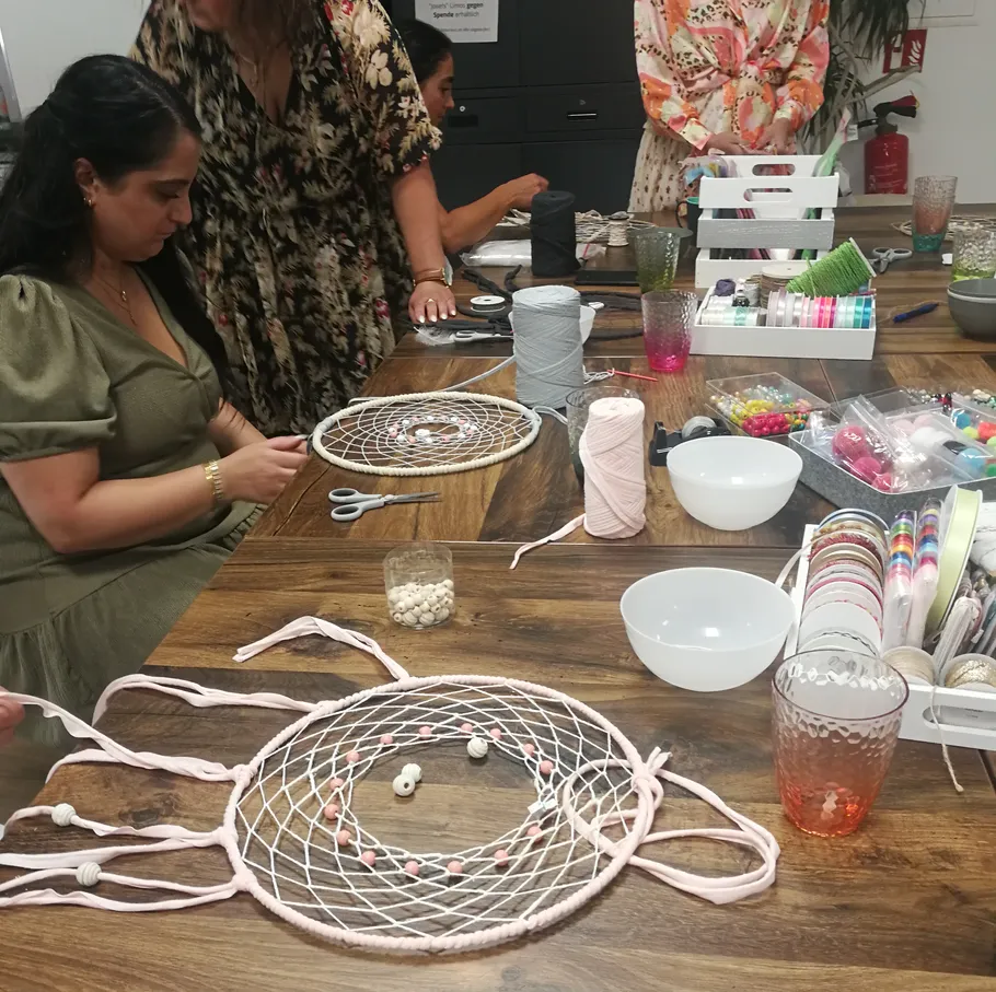 Leute basteln Traumfänger an einem Holztisch.