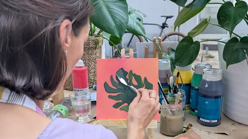 Woman painting leaf canvas in a garden.