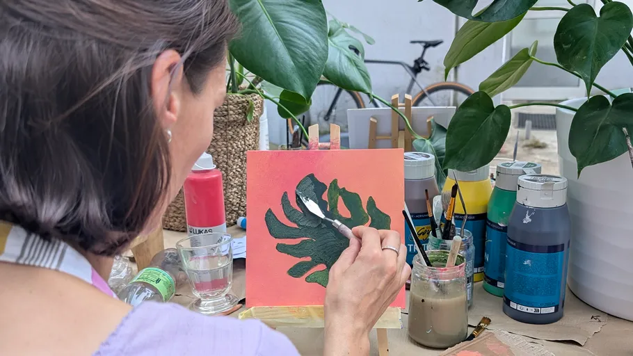 Woman painting leaf canvas in a garden.
