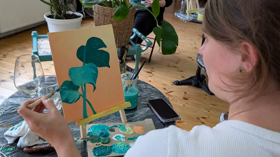 Woman painting leaves on canvas indoors.